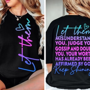 May include: Black sweatshirt with the text "Let them" in a gradient of blue to pink. The back of the shirt has the text "Let them misunderstand you, judge you, gossip and doubt you. Your worth has already been affirmed by God. Keep Shining."