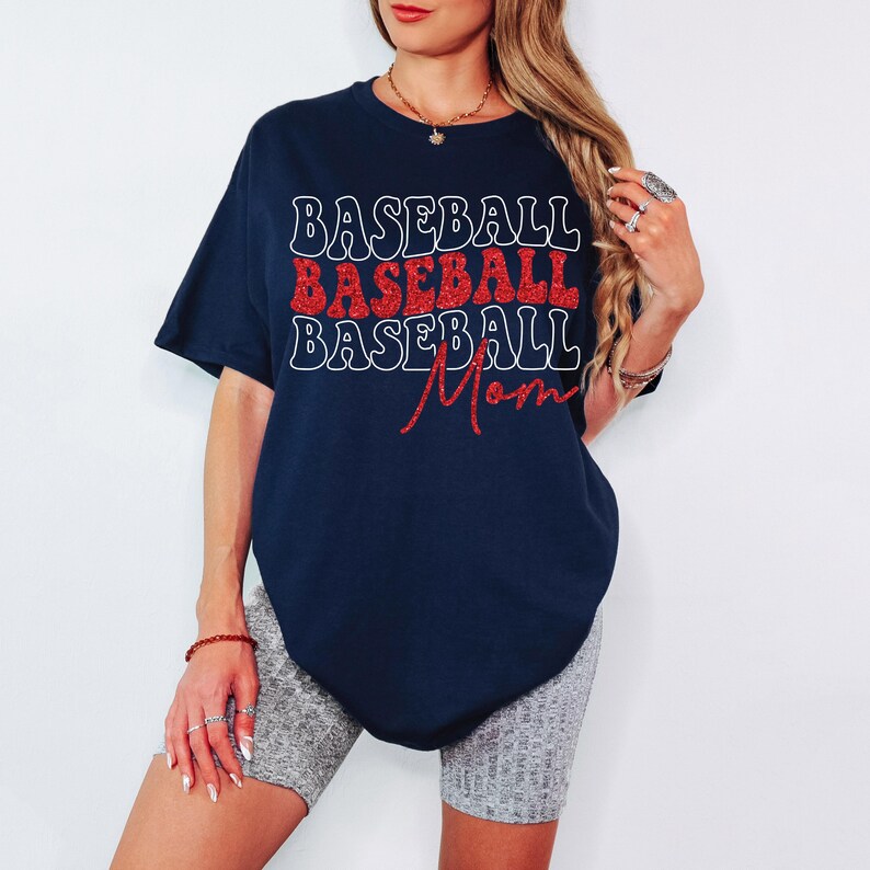 Pu&ograve; includere: Una maglietta blu navy con il testo "BASEBALL BASEBALL BASEBALL Mom" in lettere bianche e rosse glitter.