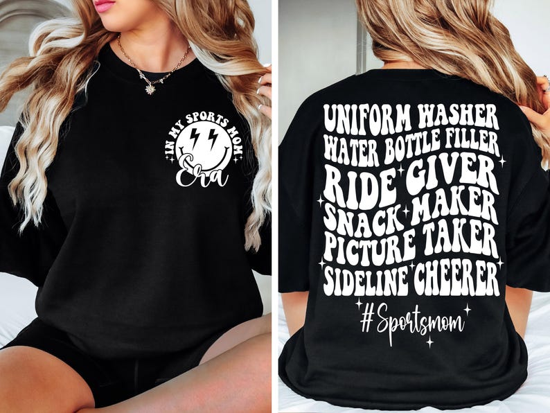 May include: Black t-shirt with white text that reads "In my sports mom era" with a smiley face and lightning bolts on the front. The back of the shirt reads "Uniform washer, water bottle filler, ride giver, snack maker, picture taker, sideline cheerleader #Sportsmom".