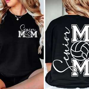 May include: Black t-shirt with white text that says "Senior Mom" and a volleyball graphic. The back of the shirt has the text "Senior Mom" with a volleyball graphic and a heart.