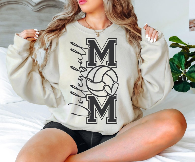 May include: A cream-colored sweatshirt with the words "Volleyball Mom" and a volleyball with a heart design printed on the front.