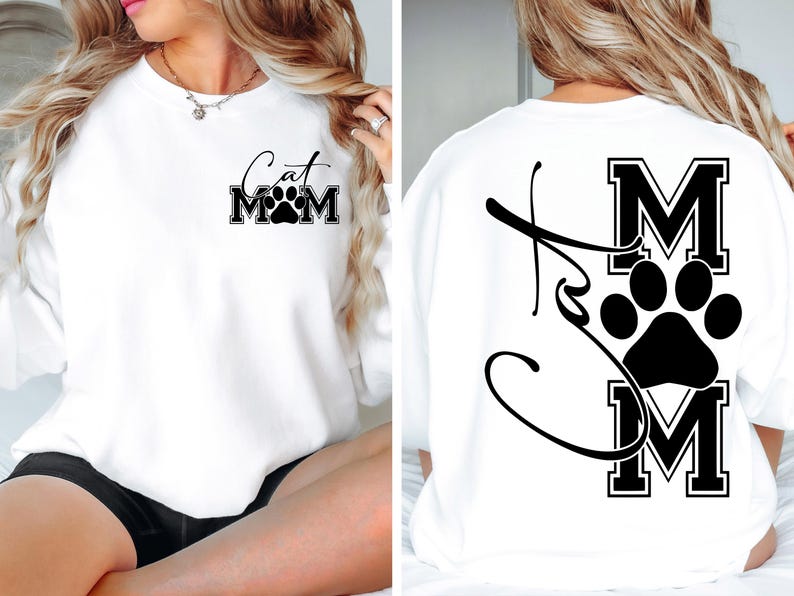 May include: White sweatshirt with the text "Cat Mom" and a paw print design. The text is in a black, stylized font. The back of the sweatshirt also features a paw print and the letters "MOM" in a black, block font.