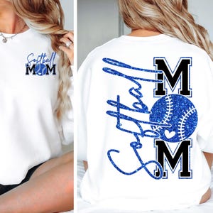 May include: White sweatshirt with blue glitter text and a baseball graphic. The front features "Softball Mom" with a baseball graphic. The back displays "Softball" in script, with "MOM" and a baseball graphic.