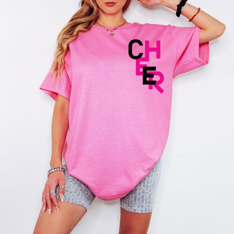 May include: Pink oversized t-shirt with the word "CHEER" printed on the front in black and pink letters.