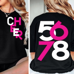 May include: Black t-shirt with the word "CHEER" in pink vertical lettering on the front and the numbers "5678" in white and pink on the back.