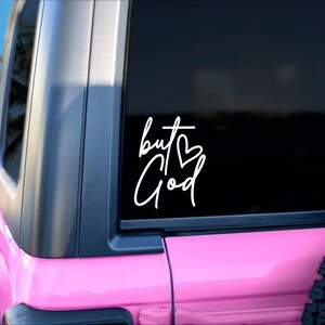 May include: A pink car with a black window and a white vinyl decal that says "but God" with a heart symbol.