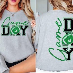 K&ouml;nnte beinhalten: Ein hellgraues Sweatshirt mit den Worten "Game Day" in gr&uuml;nem Glitzerschriftzug und schwarzen Blockbuchstaben. Ein gr&uuml;ner Glitzer-Football befindet sich in der Mitte des Wortes "Day". Auf der R&uuml;ckseite des Sweatshirts stehen ebenfalls die Worte "Game Day".