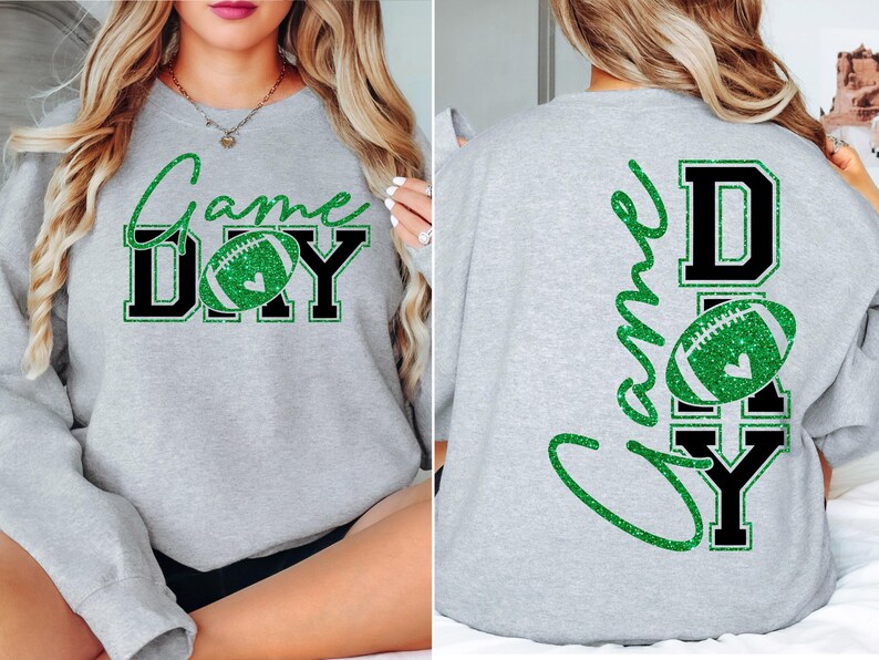 K&ouml;nnte beinhalten: Ein hellgraues Sweatshirt mit den Worten "Game Day" in gr&uuml;nem Glitzerschriftzug und schwarzen Blockbuchstaben. Ein gr&uuml;ner Glitzer-Football befindet sich in der Mitte des Wortes "Day". Auf der R&uuml;ckseite des Sweatshirts stehen ebenfalls die Worte "Game Day".