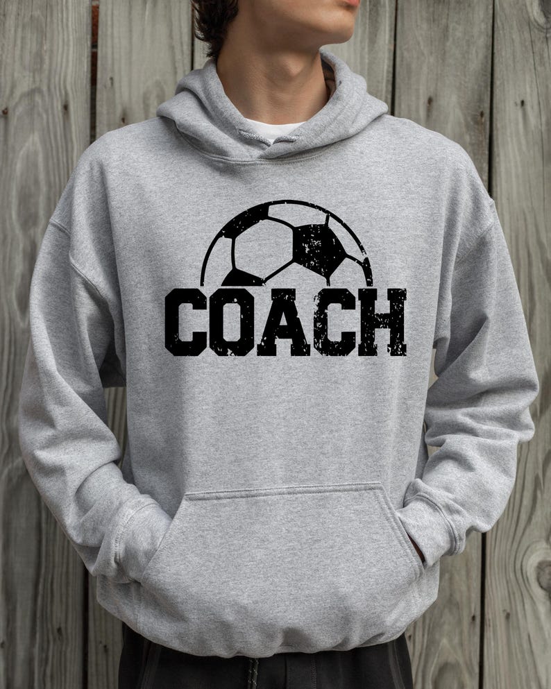 May include: A gray hooded sweatshirt with a black soccer ball graphic and the word "COACH" printed in black.