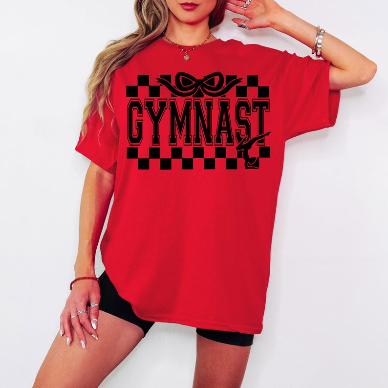 May include: Red t-shirt with a black checkered pattern, a black ribbon, and the text "GYMNAST" in black with a white outline.