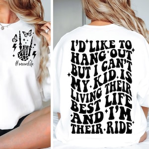 May include: White sweatshirt with black text that reads "I'd like to hang out but I can't my kid is living their best life and I'm their ride". The sweatshirt also has a small black graphic of a skeleton hand with the text "#momlife" on the front.