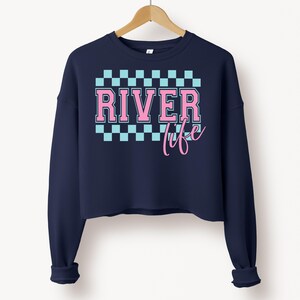 May include: A navy blue cropped sweatshirt with a pink and blue checkered pattern and the text "River life" in pink.