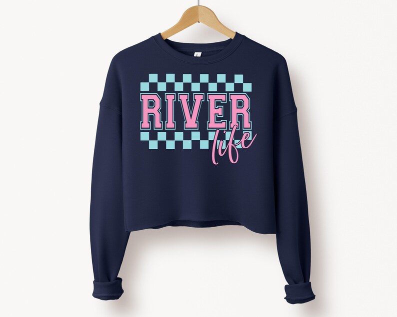 May include: A navy blue cropped sweatshirt with a pink and blue checkered pattern and the text "River life" in pink.