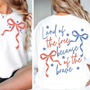May include: White sweatshirt with a red and blue bow design and blue stars. The back of the sweatshirt has the text "Land of the free because of the brave" in blue and red.