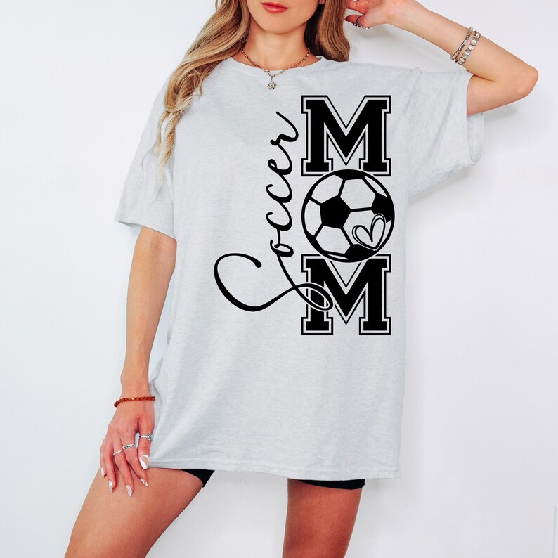 May include: A gray t-shirt with the text "Soccer Mom" in black lettering. The text is stylized with a soccer ball and a heart.