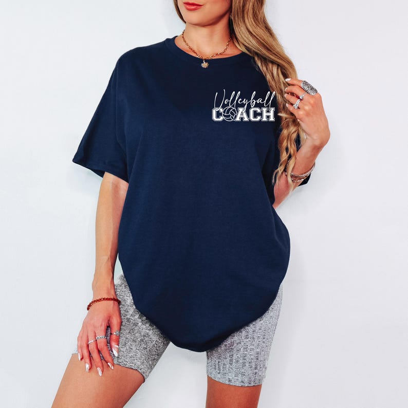 K&ouml;nnte beinhalten: Ein &uuml;berdimensioniertes T-Shirt in Marineblau mit dem Text "Volleyball Coach" in wei&szlig;en Buchstaben. Das Shirt zeigt eine kleine Volleyballgrafik.
