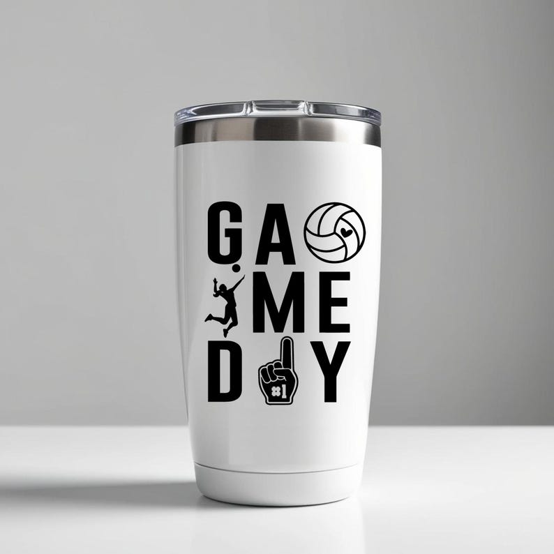 May include: White travel mug with a silver lid. The mug has the words "GAME DAY" in large black letters, a volleyball graphic, a volleyball player silhouette, and a number one foam finger.