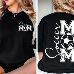May include: Black t-shirt with white text that says "Soccer Mom" with a soccer ball graphic. The back of the shirt has the text "Soccer Mom" with the letters "M" and "O" being larger and a soccer ball graphic.