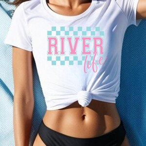 May include: White t-shirt with a blue and white checkered pattern and the text "River life" in pink letters.