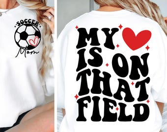 May include: White sweatshirt with black text that reads "My heart is on that field" with a red heart in the middle. The back of the sweatshirt has a black and white soccer ball with the text "Soccer Mom" and a red heart.