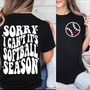 May include: Black t-shirt with white text that reads "Sorry I can't it's softball season". The back of the shirt has a white baseball with a red heart in the middle.