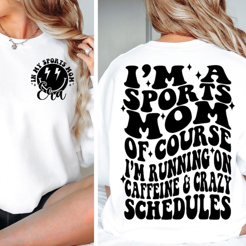 Pode incluir: Camisola branca com texto preto que diz "Eu sou uma m&atilde;e esportiva, claro que estou correndo com cafe&iacute;na e hor&aacute;rios loucos". O texto est&aacute; em um estilo de fonte retr&ocirc;. H&aacute; um design menor na frente da camiseta que diz "Na minha era de m&atilde;e esportiva" com um rosto sorridente e raios.
