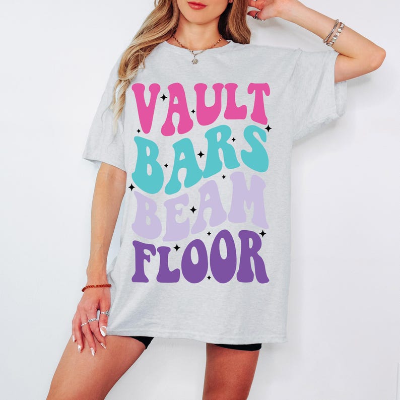 May include: A grey t-shirt with the words "VAULT BARS BEAM FLOOR" printed in pink, blue, purple, and white.