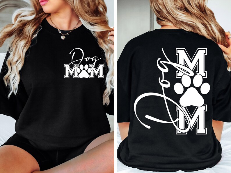 Puede incluir: Camiseta negra con una huella de pata blanca y el texto "Dog Mom" en la parte delantera. La parte posterior de la camiseta tiene una huella de pata blanca y el texto "Dog Mom" en una fuente de escritura.