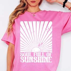 May include: Pink t-shirt with a white graphic of a sun with rays and the text "Soul Full of Sunshine".