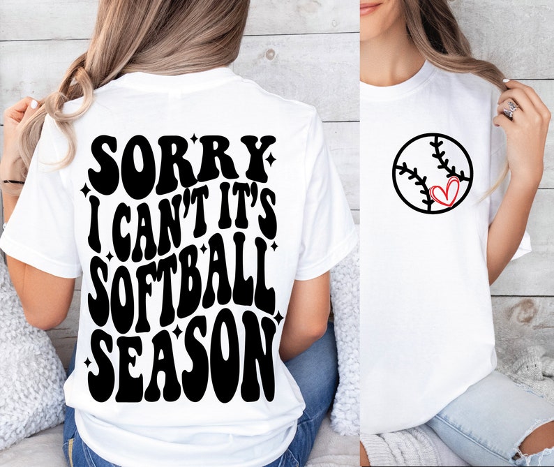 May include: White t-shirt with black text that reads "Sorry I can't it's softball season" on the back. The front of the shirt has a black and white softball with a red heart in the middle.