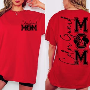 May include: Red t-shirt with black text that says "Color Guard Mom" on the front and "Color Guard MOM" vertically down the back with a graphic of crossed flags.