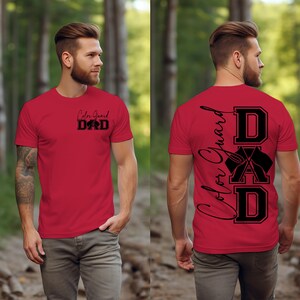 May include: Red t-shirt with black text that says "Color Guard Dad" on the front and "DAD" with a color guard symbol on the back.