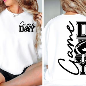 May include: White sweatshirt with the text "Game Day" and a football graphic in black. The design is on the front and back of the sweatshirt. The sweatshirt is a long-sleeved, crew neck style.