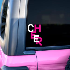 May include: Pink Jeep with a black window and a white and pink "CHEER" decal on the back window.