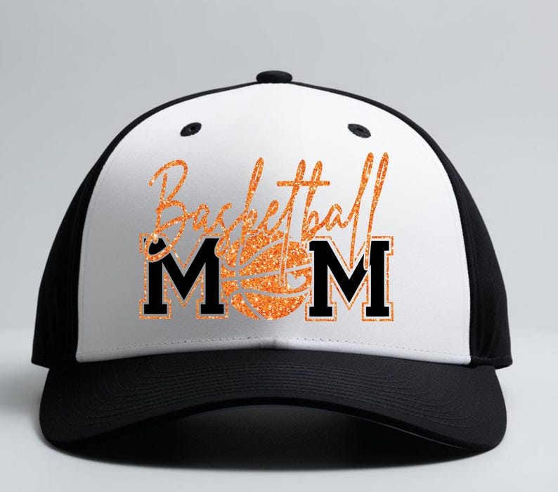 May include: A black and white baseball cap with the words "Basketball Mom" in orange glitter script. The word "MOM" is in bold black letters. A basketball graphic is in the center of the text.