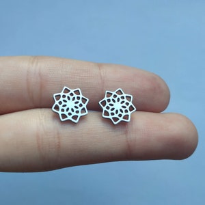 May include: A pair of silver earrings featuring a delicate, intricate mandala design.