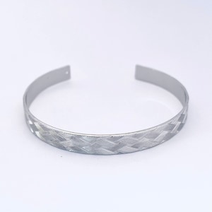 May include: A silver bangle bracelet with a woven pattern.