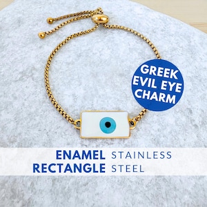 May include: Gold-toned stainless steel bracelet featuring a white enamel rectangle with a blue eye design. The bracelet has a sliding clasp for adjustable sizing. Text on the image reads: "GREEK EVIL EYE CHARM" and "ENAMEL STAINLESS RECTANGLE STEEL".
