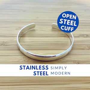 May include: A silver open cuff bracelet made of stainless steel. The bracelet is simple and modern in design. The text "OPEN STEEL CUFF" is in a blue circle on the right side of the image. The text "STAINLESS STEEL SIMPLY MODERN" is at the bottom of the image.