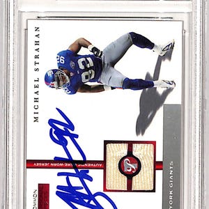 May include: A white and red sports trading card featuring a photo of Michael Strahan, a football player for the New York Giants. The card is signed in blue ink by Michael Strahan. The card is from the 2005 Topps Pristine Personal Pieces series. The card is labeled "Common".