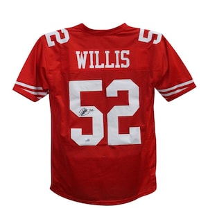 May include: Red football jersey with white lettering. The jersey has the name "WILLIS" and the number "52" on the back. The jersey is signed in black ink.