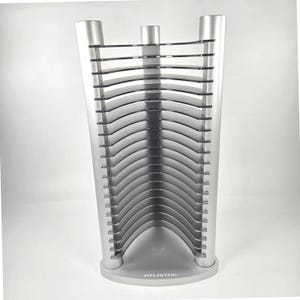 May include: A silver media storage rack with a curved design featuring multiple horizontal black slots for organizing discs. The base is semi-circular and features the word ATLANTIC printed in white on the front center of the stand.