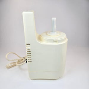 May include: Off-white food processor with a tall, vertical handle and a round base. The appliance has a blade attachment and a power cord. The design is simple and functional, suitable for various kitchen tasks.