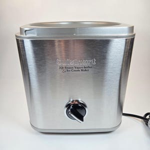 May include: A stainless steel Cuisinart 2Qt Frozen Yogurt-Sorbet & Ice Cream Maker. The appliance has a brushed metal finish, a black control knob, and a silver top. The text "Cuisinart" and product details are printed on the front.