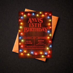 May include: A birthday invitation featuring the text "ANVIS 13TH BIRTHDAY" in red, framed by multi-colored fairy lights. The invitation includes event details and an RSVP section, set against a wooden background, with an orange envelope.