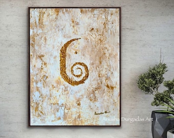 May include: Abstract painting with a gold swirl on a white and beige background. The painting is framed and hanging on a wall in a modern living room. The artist's signature is visible in the bottom right corner. "Anusha Durgadas Art" is written below the signature.
