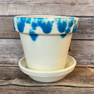 May include: White ceramic planter with a blue and white marbled design. The planter has a matching saucer.