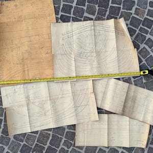 May include: A set of four vintage blueprint style paper plans for building a boat. The plans are folded and show detailed drawings of the boat's construction.