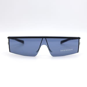 May include: Black sunglasses with a flat top and blue lenses. The sunglasses have a sleek, modern design. The brand name "EMPORIO ARMANI" is visible on the right lens.