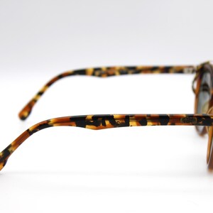 May include: Tortoise shell sunglasses with gold accents and a brown lens. The sunglasses have a thin metal frame and a tortoiseshell pattern on the arms.